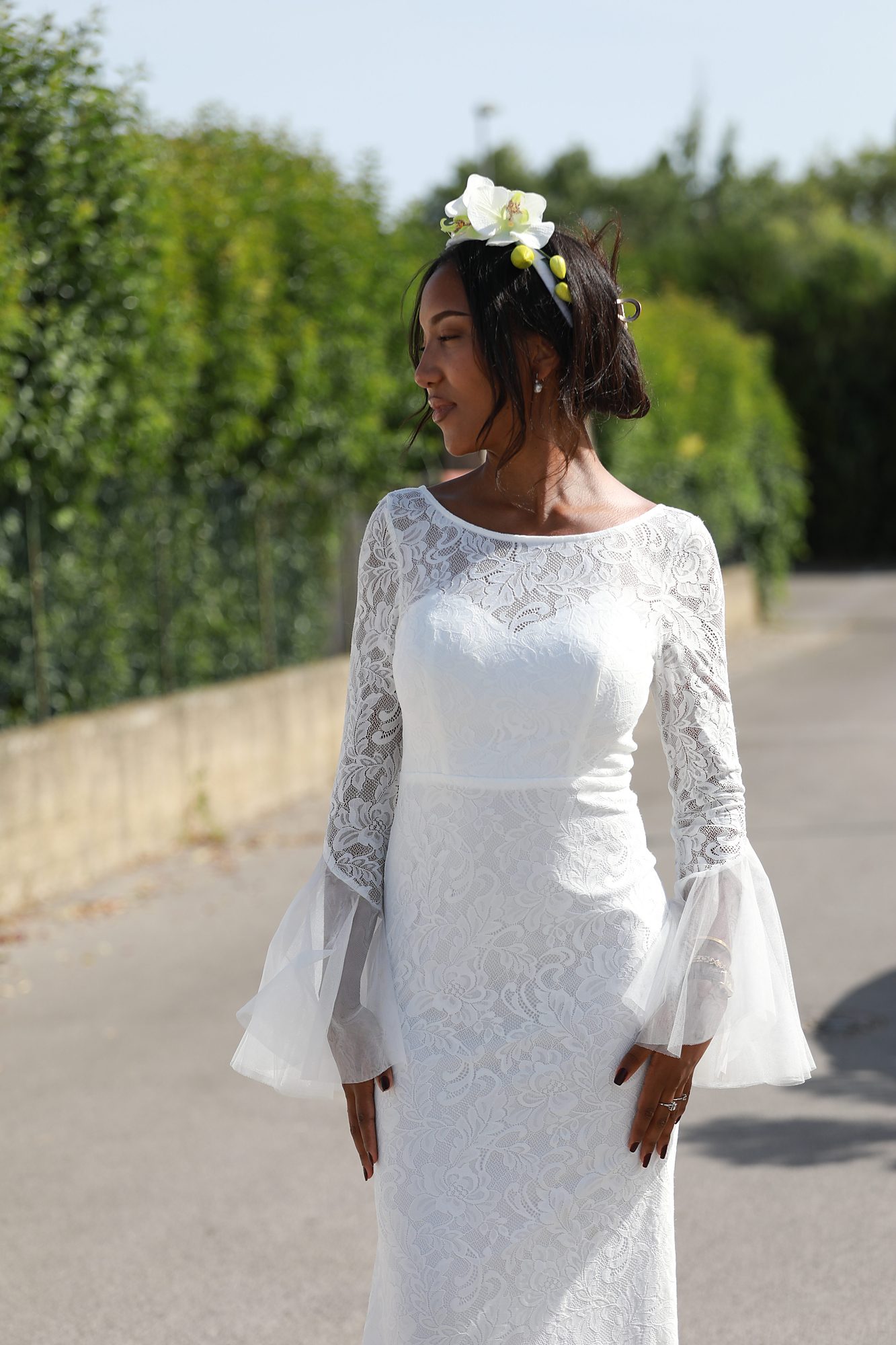 Vue de profil de la robe de mariée Solveig sur mesure, mettant en valeur la dentelle délicate, les manches transparentes et le voile fluide réalisés artisanalement chez Princesse Couture.