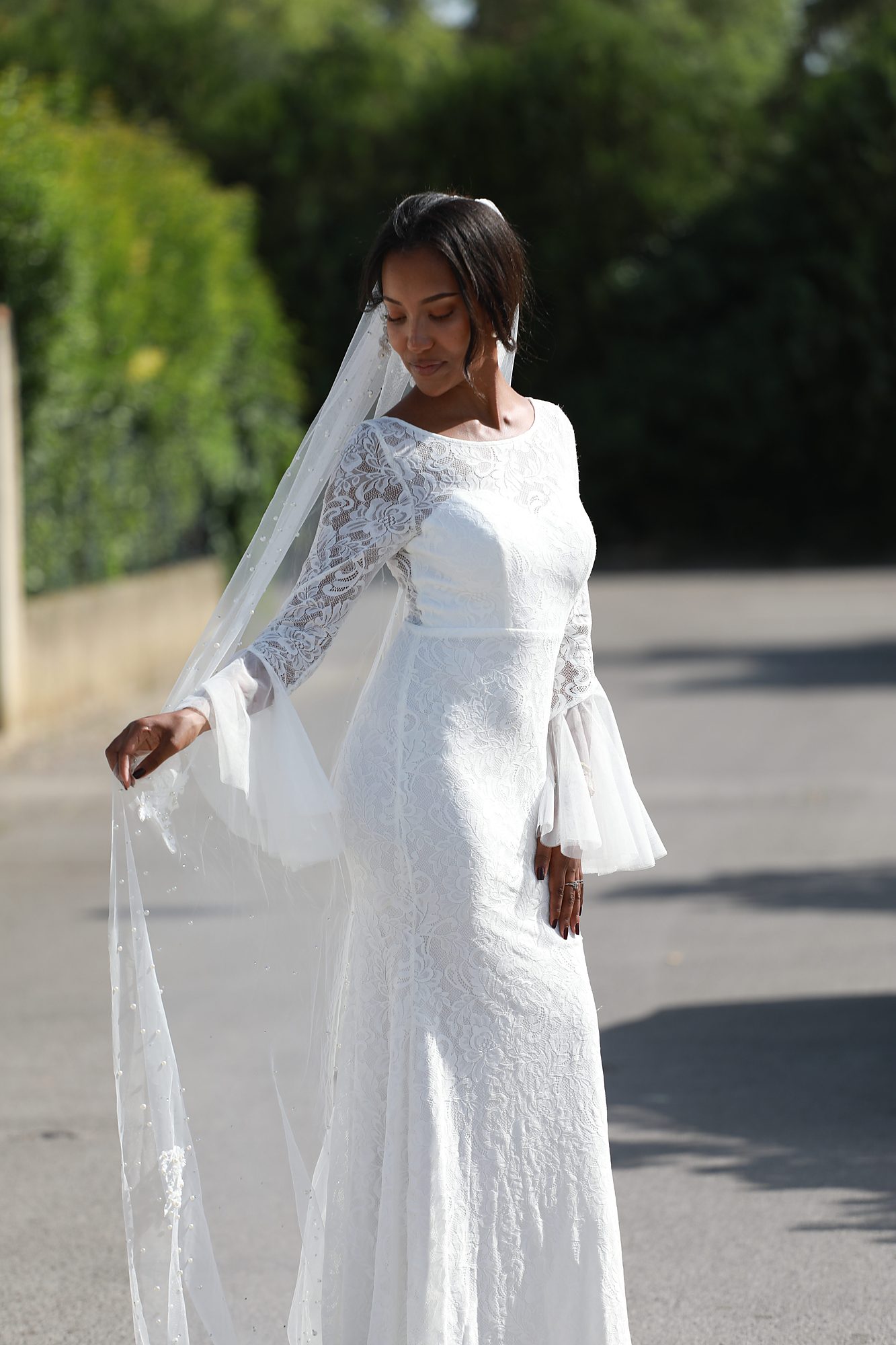 Vue de profil de la robe de mariée Solveig sur mesure, mettant en valeur la dentelle délicate, les manches transparentes et le voile fluide réalisés artisanalement chez Princesse Couture.